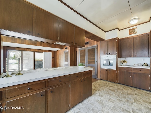 kitchen with oven, light tile patterned flooring, and dark brown cabinets