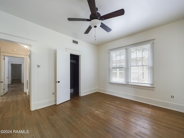 unfurnished bedroom with dark hardwood / wood-style flooring, a closet, and ceiling fan