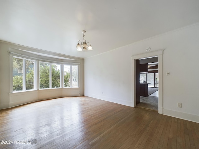 empty room featuring an inviting chandelier, dark wood-type flooring, and ornamental molding