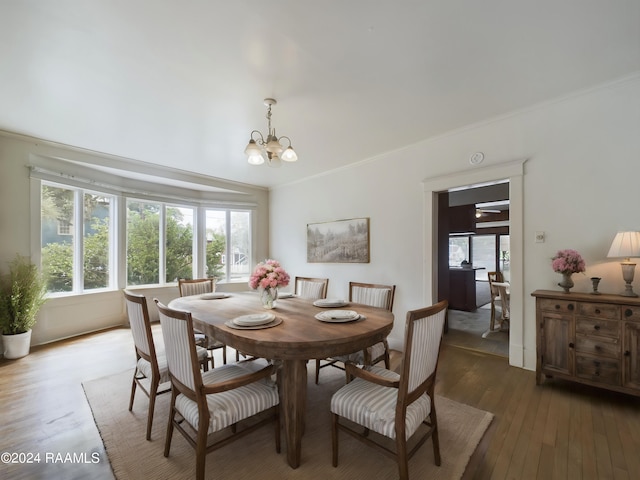 dining area with ornamental molding, wood-type flooring, and a chandelier