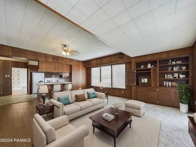 carpeted living room with ceiling fan and wooden walls