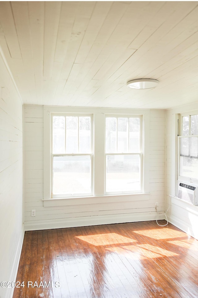 empty room featuring wood ceiling, wooden walls, hardwood / wood-style floors, and cooling unit