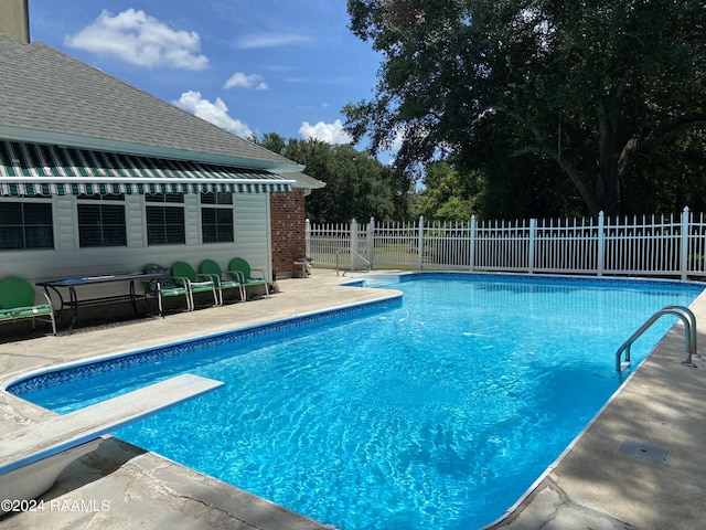 view of pool featuring a diving board and a patio