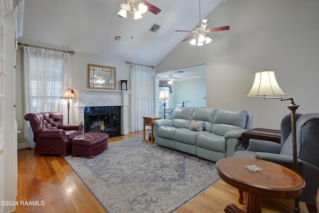 living room with ceiling fan, a fireplace, high vaulted ceiling, and light hardwood / wood-style flooring