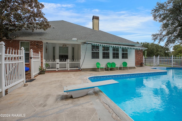 view of swimming pool with a patio, a diving board, and ceiling fan