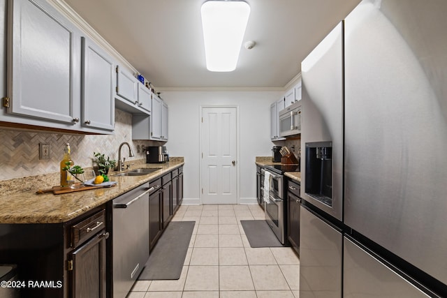 kitchen with light tile patterned flooring, sink, tasteful backsplash, appliances with stainless steel finishes, and light stone countertops