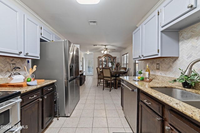 kitchen with sink, light tile patterned floors, stainless steel appliances, light stone counters, and white cabinets