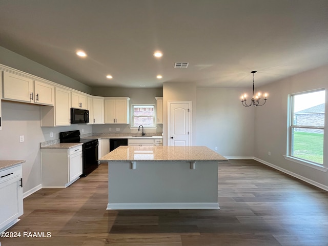 kitchen featuring sink, black appliances, pendant lighting, white cabinets, and a kitchen island