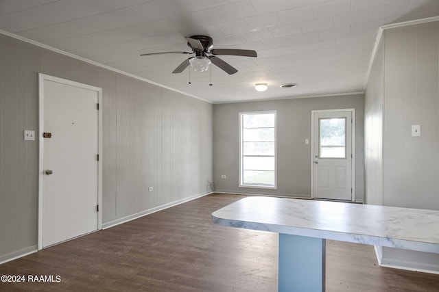 foyer with wooden walls, dark wood-type flooring, ceiling fan, and ornamental molding