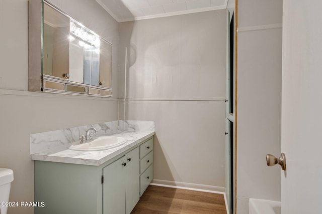 bathroom with vanity, toilet, ornamental molding, and wood-type flooring