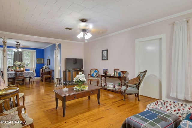 living room with ceiling fan, crown molding, and light wood-type flooring