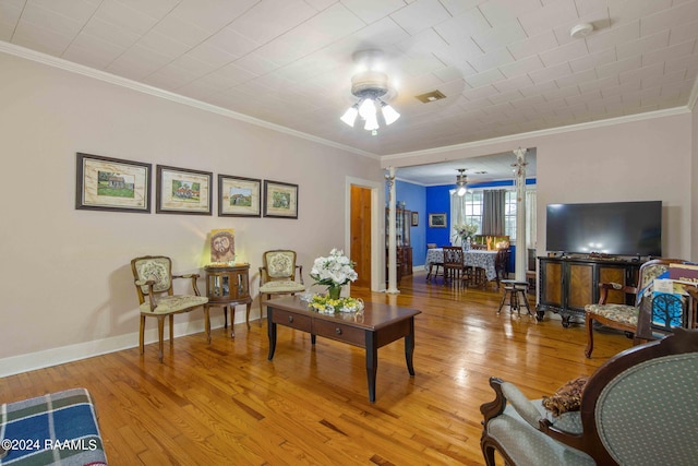 living room featuring wood-type flooring, ornamental molding, and ceiling fan