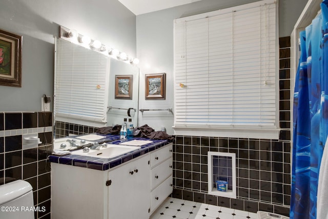 bathroom featuring vanity, toilet, and tile walls