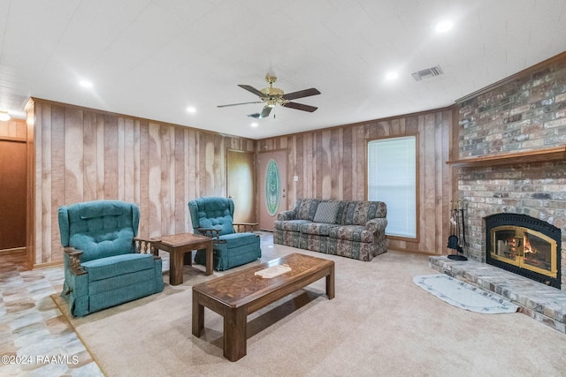 living room featuring ceiling fan, a brick fireplace, and wooden walls