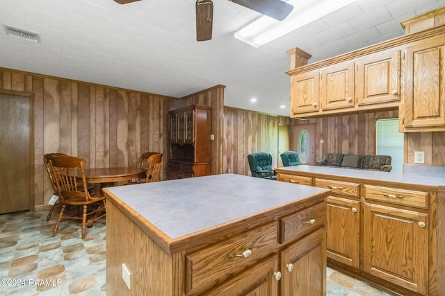 kitchen featuring a kitchen island, wood walls, and ceiling fan