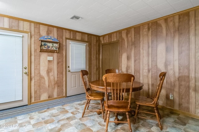 dining room featuring crown molding and wood walls