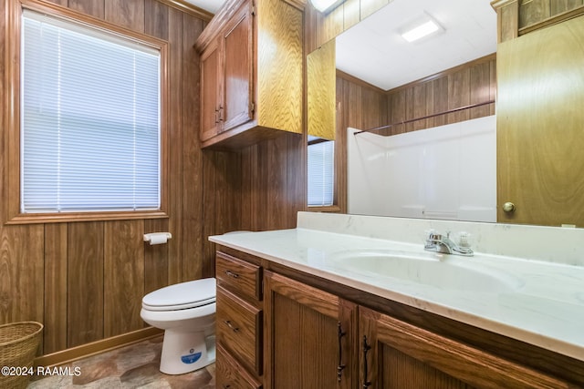 bathroom with walk in shower, wood walls, vanity, and toilet