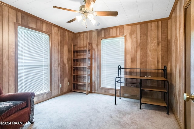 living area with ceiling fan, crown molding, and light colored carpet