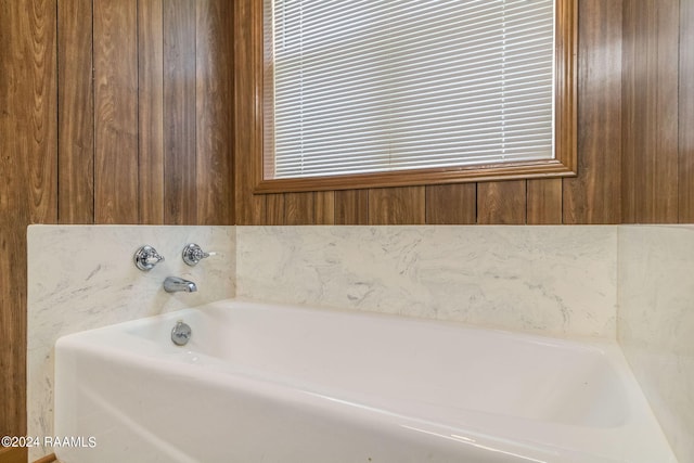 bathroom featuring a tub and wood walls