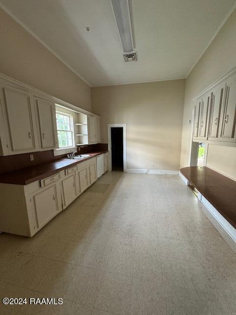 kitchen featuring ornamental molding, sink, white cabinets, and light tile patterned floors