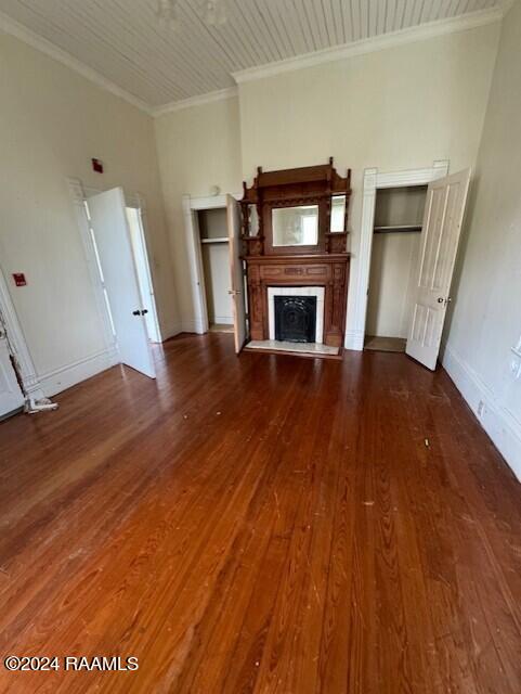 unfurnished living room with dark wood-type flooring and crown molding