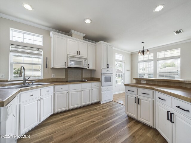 kitchen with visible vents, light wood-type flooring, ornamental molding, white appliances, and a sink