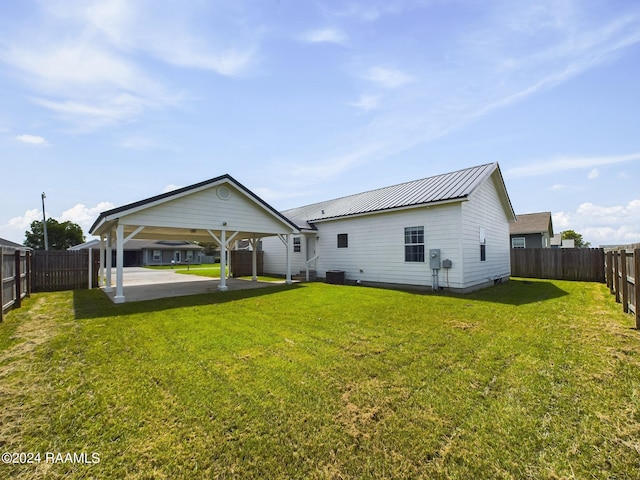 back of house with metal roof, a patio, a lawn, and a fenced backyard