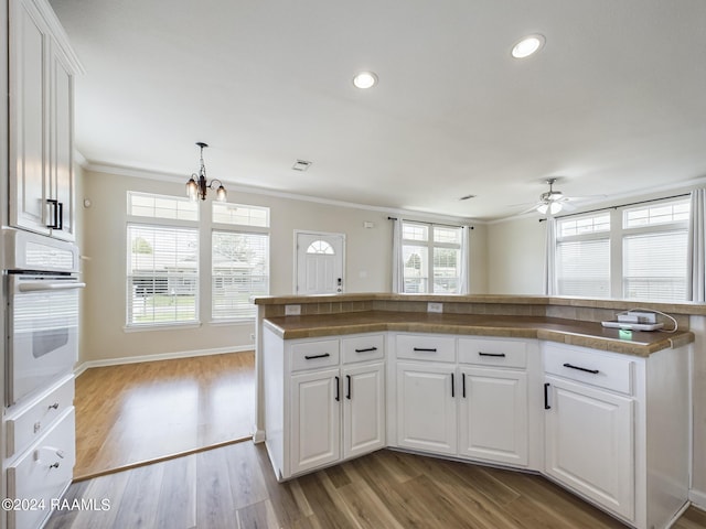kitchen with oven, wood finished floors, white cabinetry, recessed lighting, and crown molding