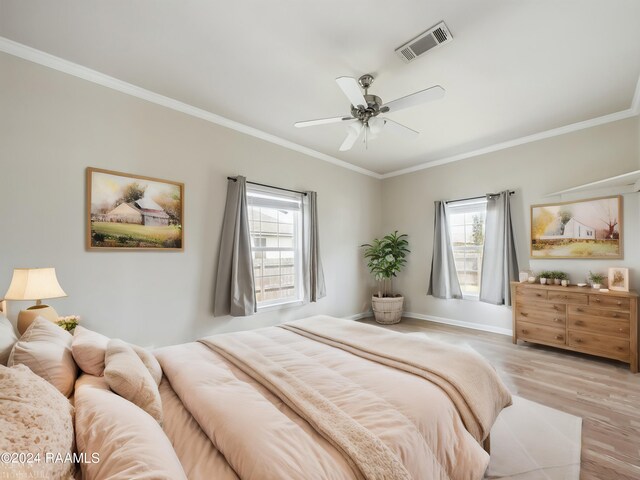 bedroom featuring visible vents, a ceiling fan, wood finished floors, crown molding, and baseboards
