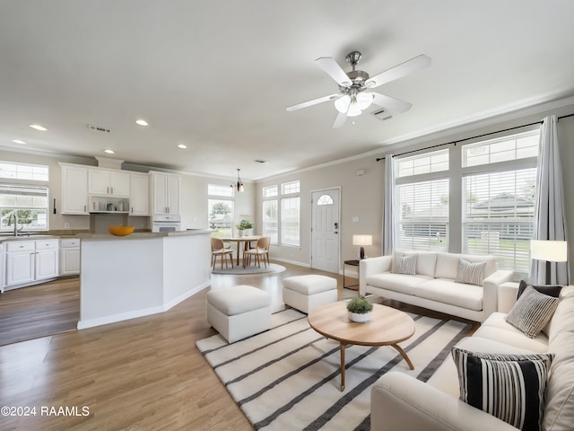 living room featuring light wood-style flooring, recessed lighting, visible vents, and ornamental molding