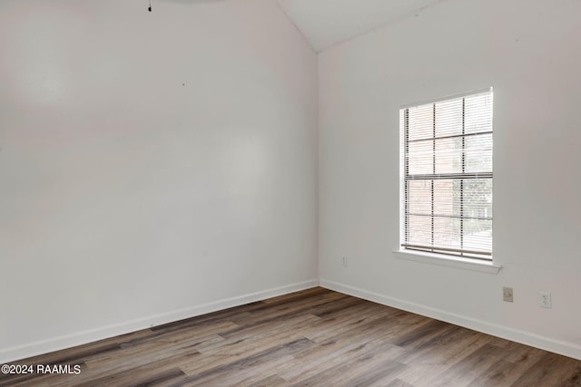 spare room with baseboards and wood finished floors