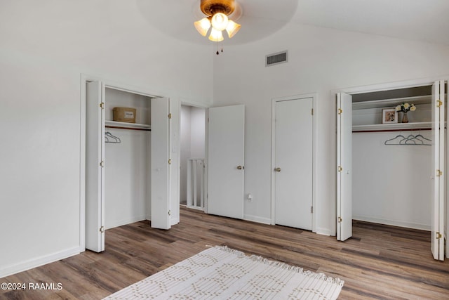 unfurnished bedroom featuring wood finished floors, visible vents, two closets, and baseboards