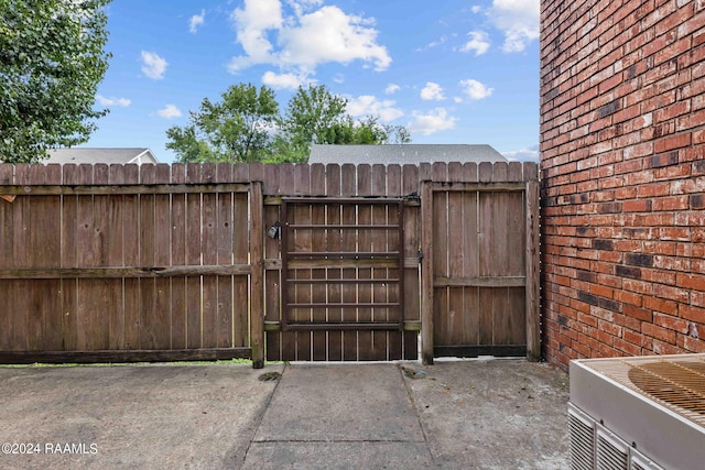 view of gate with cooling unit and fence