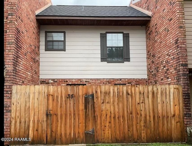 view of side of home with fence and a shingled roof