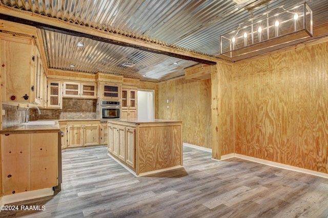 kitchen with light hardwood / wood-style floors, light brown cabinetry, beam ceiling, oven, and sink