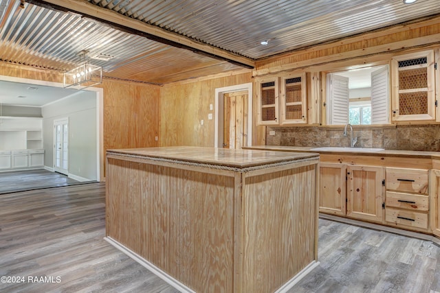 kitchen with a center island, light brown cabinetry, light hardwood / wood-style floors, beamed ceiling, and sink