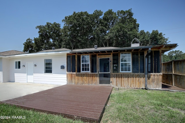 view of front of house with a deck, a front yard, and a sunroom