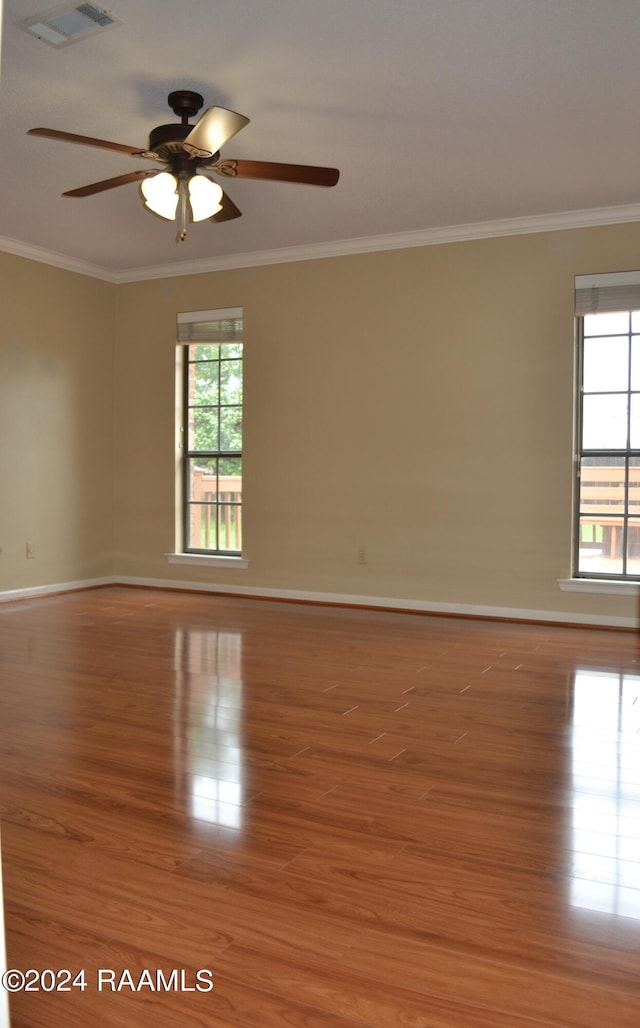 spare room featuring crown molding, plenty of natural light, ceiling fan, and wood-type flooring