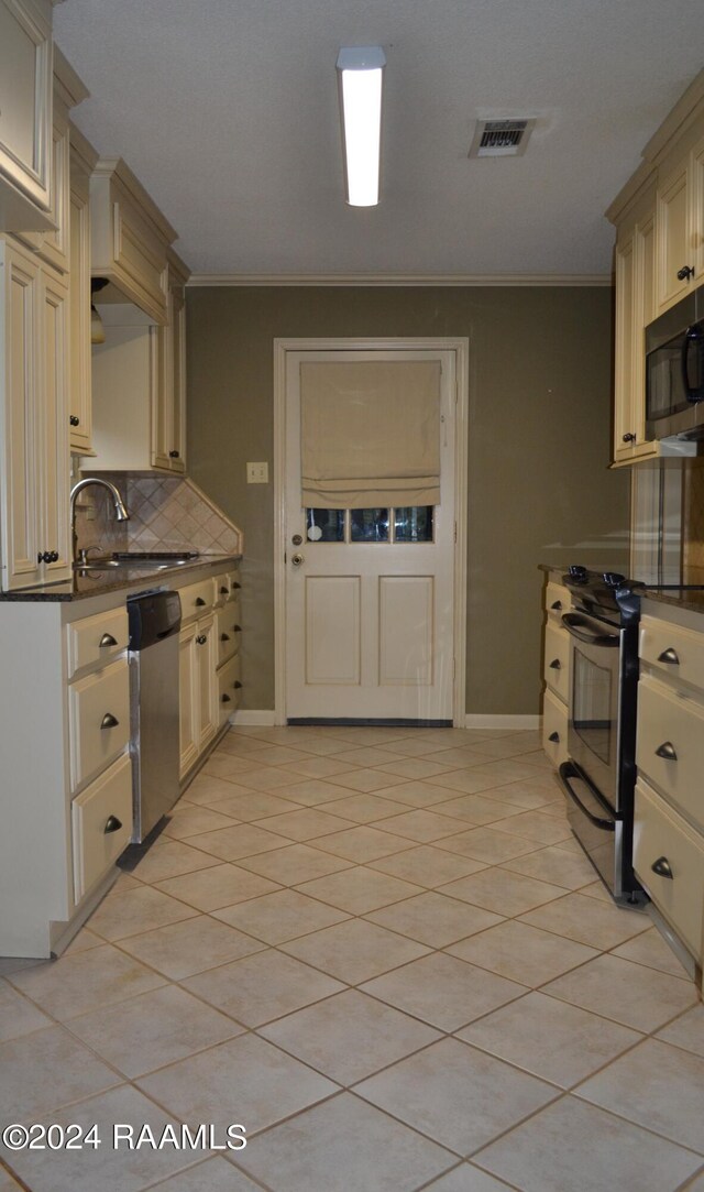 kitchen with appliances with stainless steel finishes, light tile patterned floors, sink, and cream cabinetry