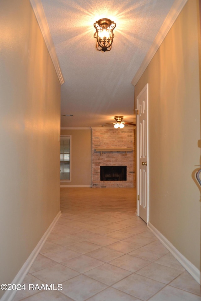 hall with light tile patterned floors, ornamental molding, and a textured ceiling