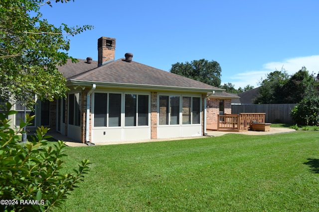 rear view of house featuring a yard and a sunroom