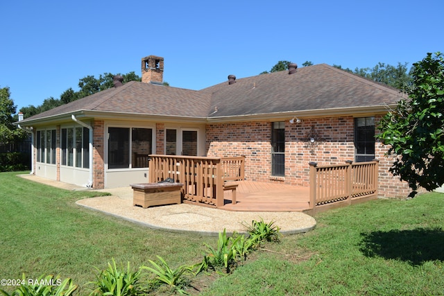 rear view of property with a sunroom, a lawn, and a wooden deck