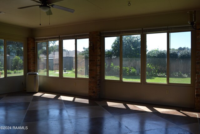 unfurnished sunroom featuring ceiling fan and plenty of natural light