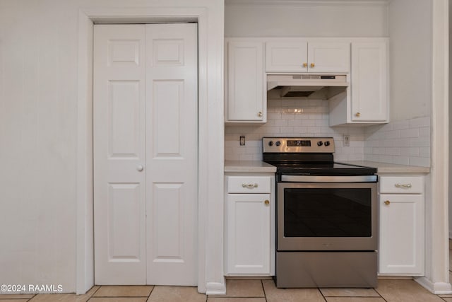 kitchen featuring decorative backsplash, electric range, wall chimney range hood, light tile patterned floors, and white cabinets