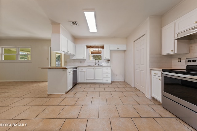 kitchen featuring backsplash, white cabinets, appliances with stainless steel finishes, light tile patterned floors, and kitchen peninsula