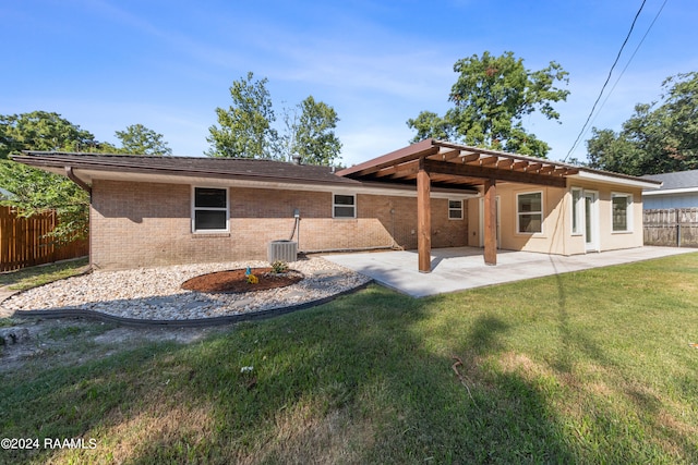 back of house with central AC, a patio area, and a lawn