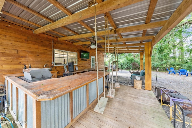 interior space featuring a bar, ceiling fan, and a wooden deck