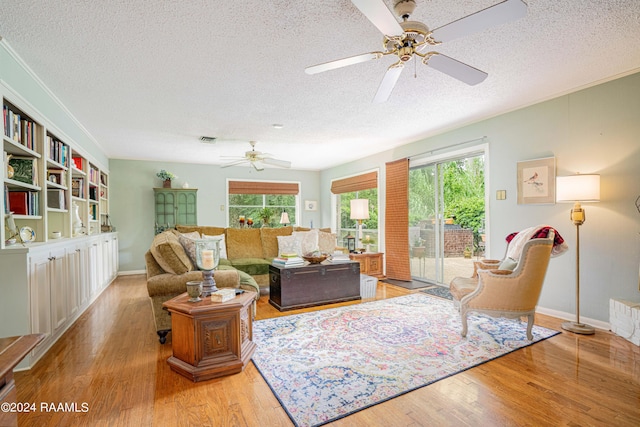 living room with ceiling fan, a textured ceiling, and light wood-type flooring