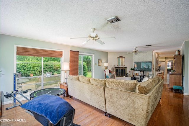 living room featuring ceiling fan, wood-type flooring, and a textured ceiling