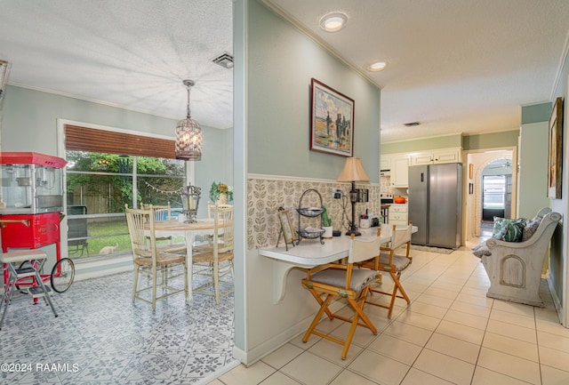 kitchen with crown molding, a wealth of natural light, white cabinets, and stainless steel refrigerator